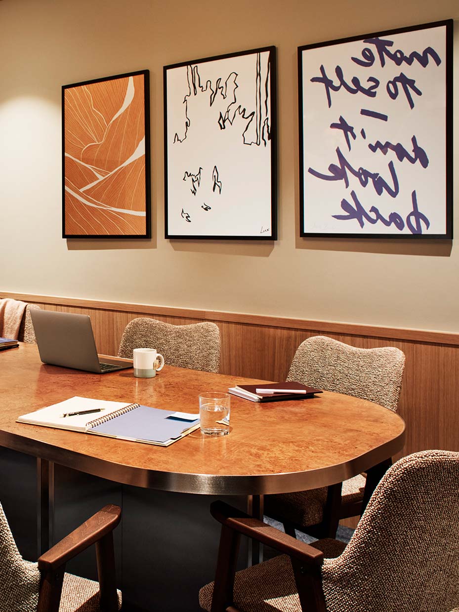 Just The One private meeting room with a rounded wooden table and framed artwork