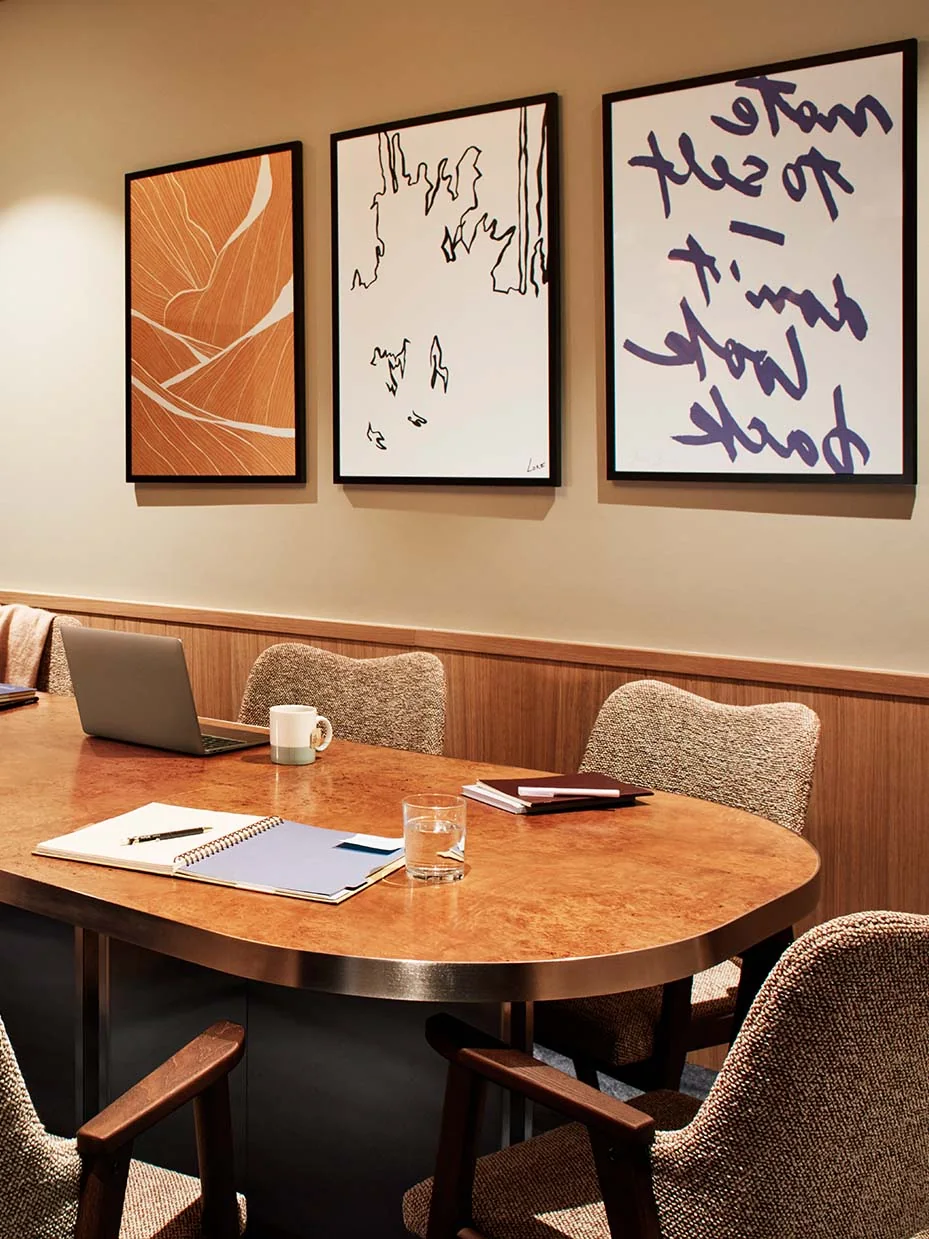 Just The One private meeting room with a rounded wooden table and framed artwork