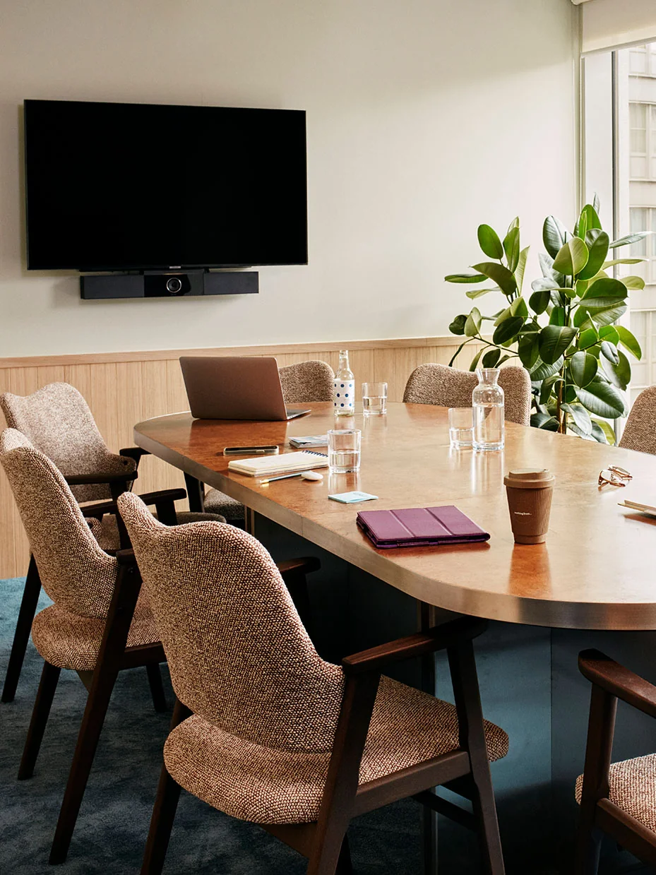 The Little One meeting room with a wooden table, chairs, screen and plants